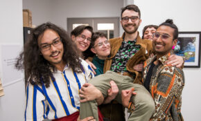 A group of ECU students lift one of the friends in the air as they smile for the camera.